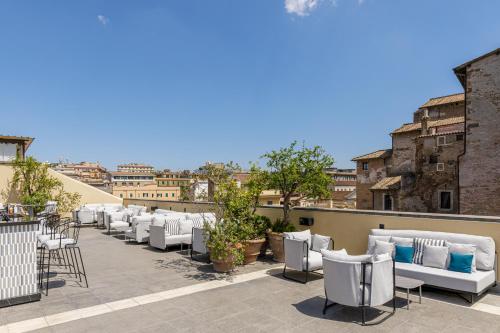 a patio with white chairs and tables on a roof at Room Mate Collection Mia, Rome Colosseum in Rome