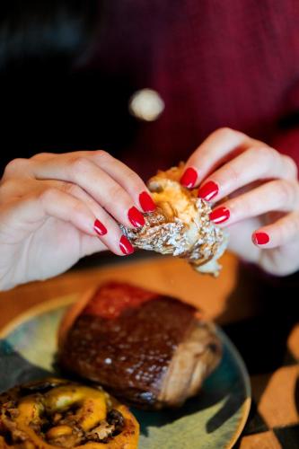 a woman with red nail polish holding a sandwich at Bienheureux Hôtel & Restaurant in Wasquehal