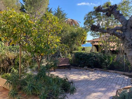 un parc avec un banc, des arbres et l'océan dans l'établissement St Raphaël Boulouris maison bord de mer Damalix, à Saint-Raphaël