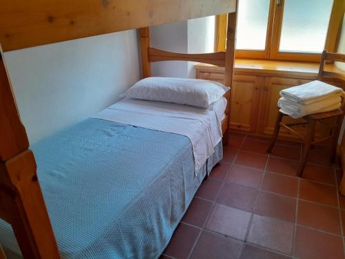 a small bedroom with a bunk bed and a chair at Chiesa in Valmalenco Vassalini 1 in Caspoggio