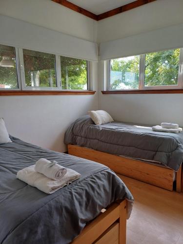 two beds in a room with two windows at Casaquinta La Morena in Azul