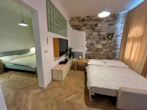 a bedroom with two beds and a stone wall at Apartmány Naxarův dvůr in Horažďovice