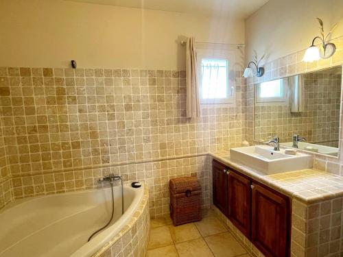 a bathroom with a bath tub and a sink at Villa des Antonins in Saint-Gilles