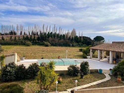 a building in a field with trees in the background at Villa des Antonins in Saint-Gilles