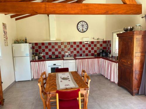 a kitchen with a table and a clock on the wall at Villa des Antonins in Saint-Gilles