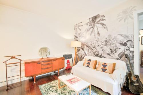 - un salon avec un canapé blanc et une guitare dans l'établissement Le Romantisme à la Française, à Paris