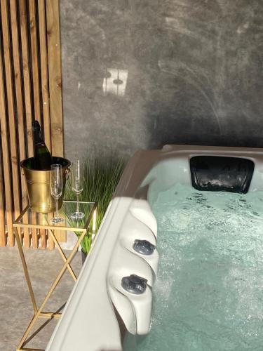 une baignoire avec une bouteille de vin et une table dans l'établissement Love You Suite Romantique Spa 25min du futuroscope, à Oyré
