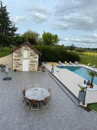 un patio avec une table et des chaises à côté d'une piscine dans l'établissement Love You Suite Romantique Spa 25min du futuroscope, à Oyré