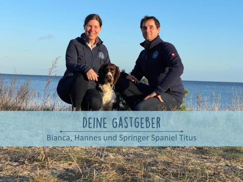 two people and a dog sitting behind a sign at Höfthus 9 Holla die Boddenfee Meerblick Terrasse mit Hund die Natur genießen in Alt Reddevitz