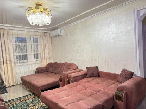a living room with two brown couches and a chandelier at Nugzar House Chakvi - 2 Bedrooms in Chakvi