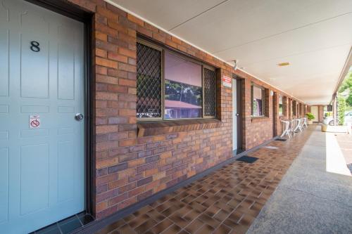 an empty hallway of a brick building with a white door at Abbey Motor Inn in Grafton