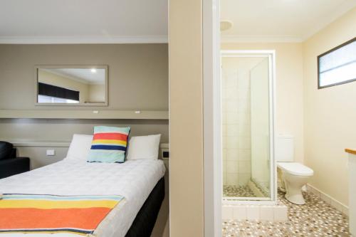a bedroom with a bed and a bathroom with a mirror at Abbey Motor Inn in Grafton