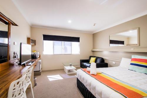 a bedroom with a bed and a desk and a couch at Abbey Motor Inn in Grafton