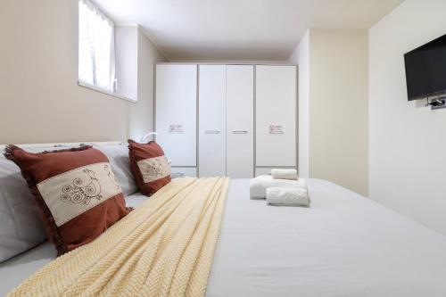 a white bedroom with a large white bed with pillows at Rosa dei Venti 2 in Alghero