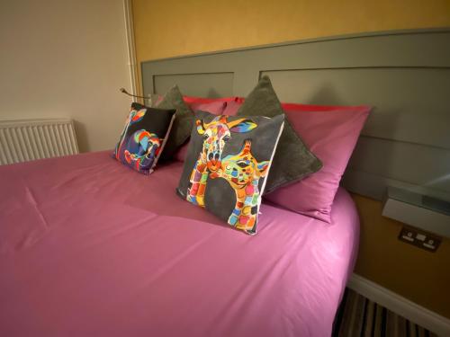 a pink bed with four pillows on top of it at Sanctuary Rooms in Brightlingsea
