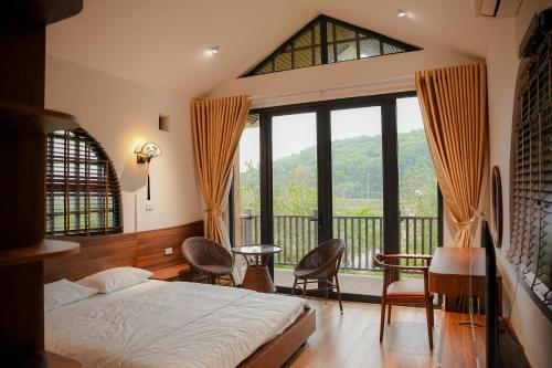 a bedroom with a bed and a large window at Nghỉ dưỡng tại Làng Văn hóa- Du lịch các dân tộc Việt Nam in Ba Vì