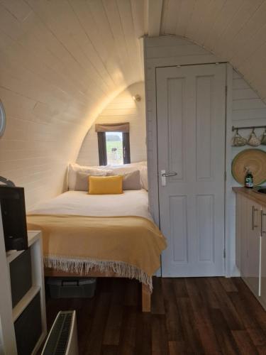 a bedroom with a bed with a yellow pillow on it at Jerusalem Farm Pods in Tranent