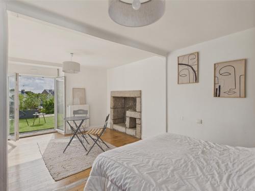 une chambre blanche avec un lit et une cheminée dans l'établissement Maison pour 6 avec jardin - Centre de Névez, à Névez