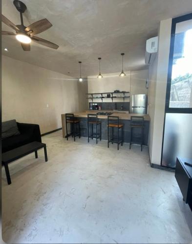 a living room with a ceiling fan and a kitchen at Villa Colibríes in Chelem