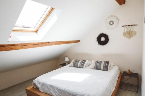 une chambre avec un lit blanc dans un grenier dans l'établissement Le Trèfle proche de Genève et Annecy, à Beaumont