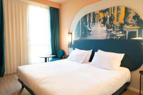 a bedroom with a white bed with a painting on the wall at Mercure Bologna Centro in Bologna