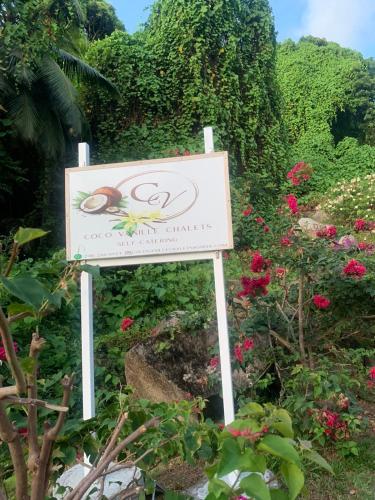 a sign in front of a garden with flowers at Coco Vanille Chalets in Takamaka