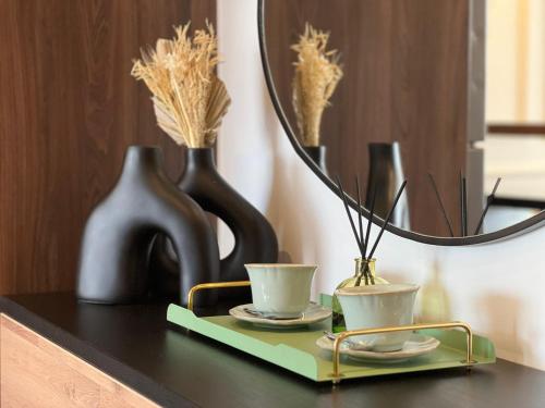 a table with two cups and a mirror and vases at Dynasty Estate, Appartements avec Terrasse et vue sur Twin Center in Maarif