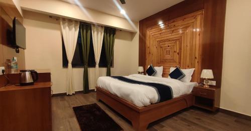 a bedroom with a large bed with a wooden headboard at Aashiyana- The White Hill Hotel in Shitlakhet