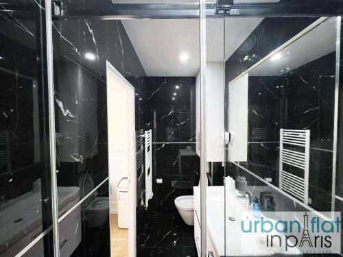 La salle de bains est pourvue de murs en marbre noir et de toilettes. dans l'établissement Urban Flat 107 - Sublime 4 Bedroom Opera Paris, à Paris