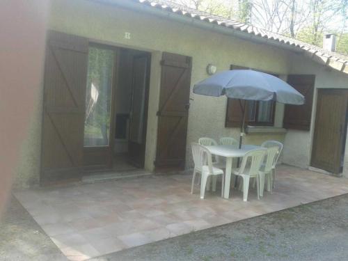 un patio con tavolo, sedie e ombrellone di Les gites de la planette - gite 9 a Saint-Amans-Valtoret