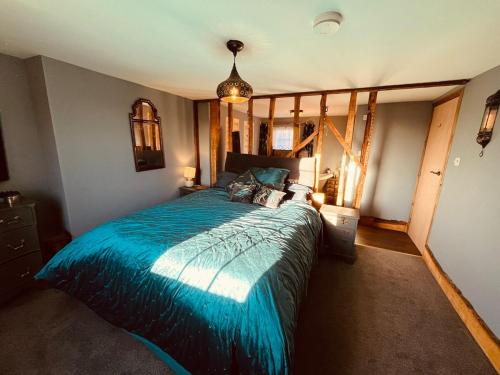 Un dormitorio con una cama grande con un edredón azul. en Adorable quirky country cottage, en Heathfield
