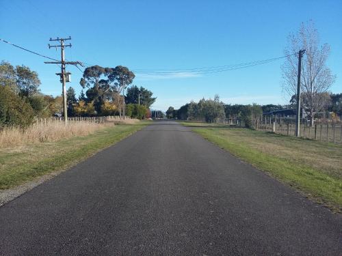 an empty road with a fence in the distance at Bumblebee Cottage in Greytown