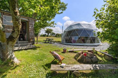 a dome tent in a field with a picnic table at Tregroes Glamping Geodomes in Manortown