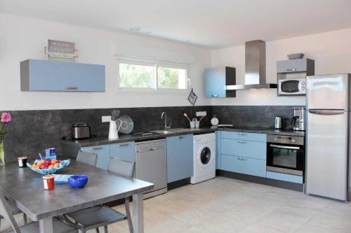 a kitchen with blue cabinets and a table in it at Banyuls in Latour-Bas-Elne