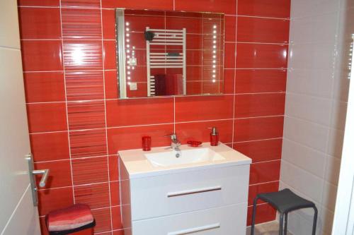a red tiled bathroom with a sink and a mirror at Collioure in Latour-Bas-Elne