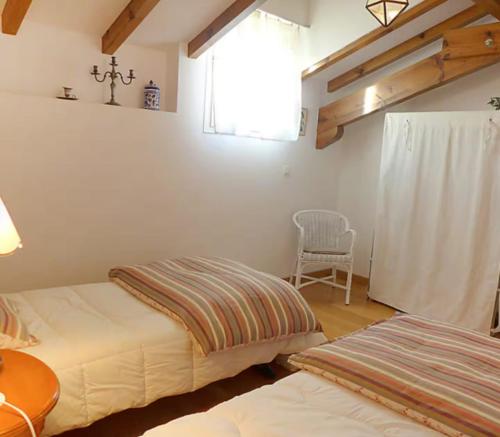 une chambre avec deux lits et une fenêtre et une chaise dans l'établissement Charming T3 with parking near the ocean, à Saint-Jean-de-Luz