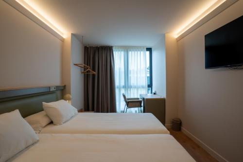 a hotel room with two beds and a television at Hotel Los Pasiegos in Hoznayo