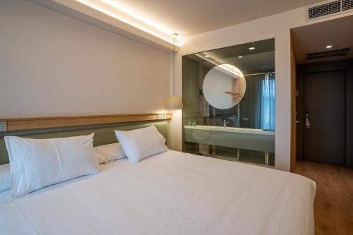 a bedroom with a large white bed and a mirror at Hotel Los Pasiegos in Hoznayo