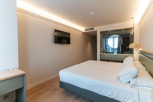 a bedroom with a white bed and a mirror at Hotel Los Pasiegos in Hoznayo
