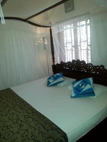a bedroom with a bed with blue and white pillows at Ahangama Eco Villa in Ahangama
