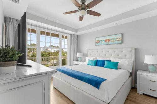 a white bedroom with a bed and a ceiling fan at Reflections 307 in Panama City Beach