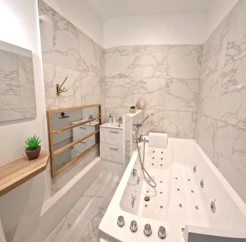 a white bathroom with a tub and a sink at Les Bons Enfants Balnéo in Rouen