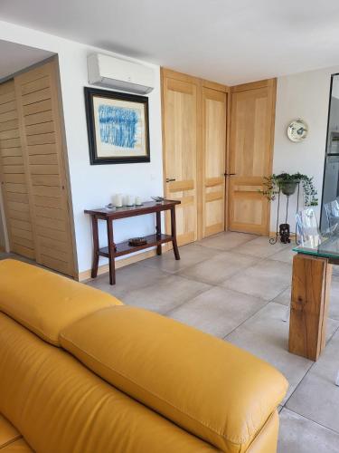 un salon avec un canapé jaune et une table dans l'établissement Appartement standing bord Sorgue, à LʼIsle-sur-la-Sorgue