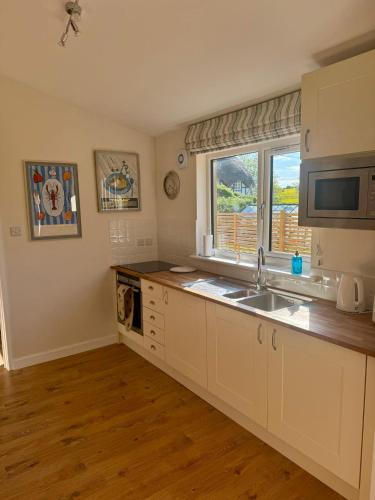 a kitchen with white cabinets and a sink and a window at Southend Long Barn in Ogbourne Saint George