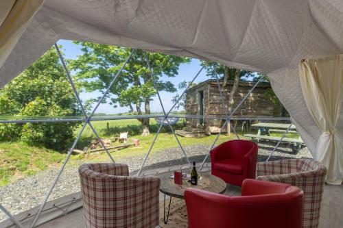 a tent with a table and chairs and a view at Tregroes Glamping Geodomes in Manortown