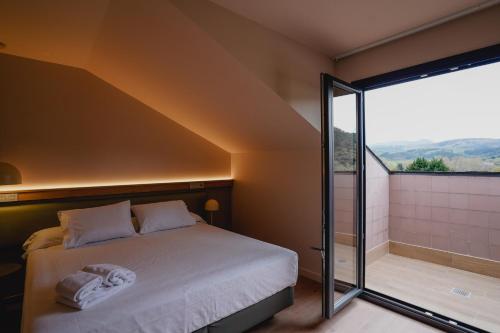 a bedroom with a bed and a large window at Hotel Los Pasiegos in Hoznayo