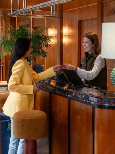 two women are standing at a counter with laptops at Hôtel La Conversation in Paris