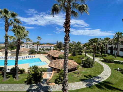 une vue d'un complexe avec piscine et palmiers dans l'établissement Appartement T2 vue mer, piscine Linguizzetta Bravone, à Linguizzetta