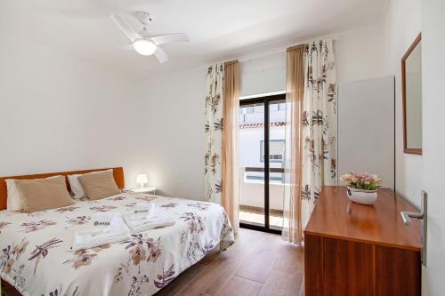 a bedroom with a bed and a dresser and a window at Casa Santos in Monte Gordo
