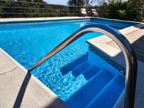 a blue swimming pool with a metal hand rail in it at Villa Marie, 8 pers, green zone, private in GRO